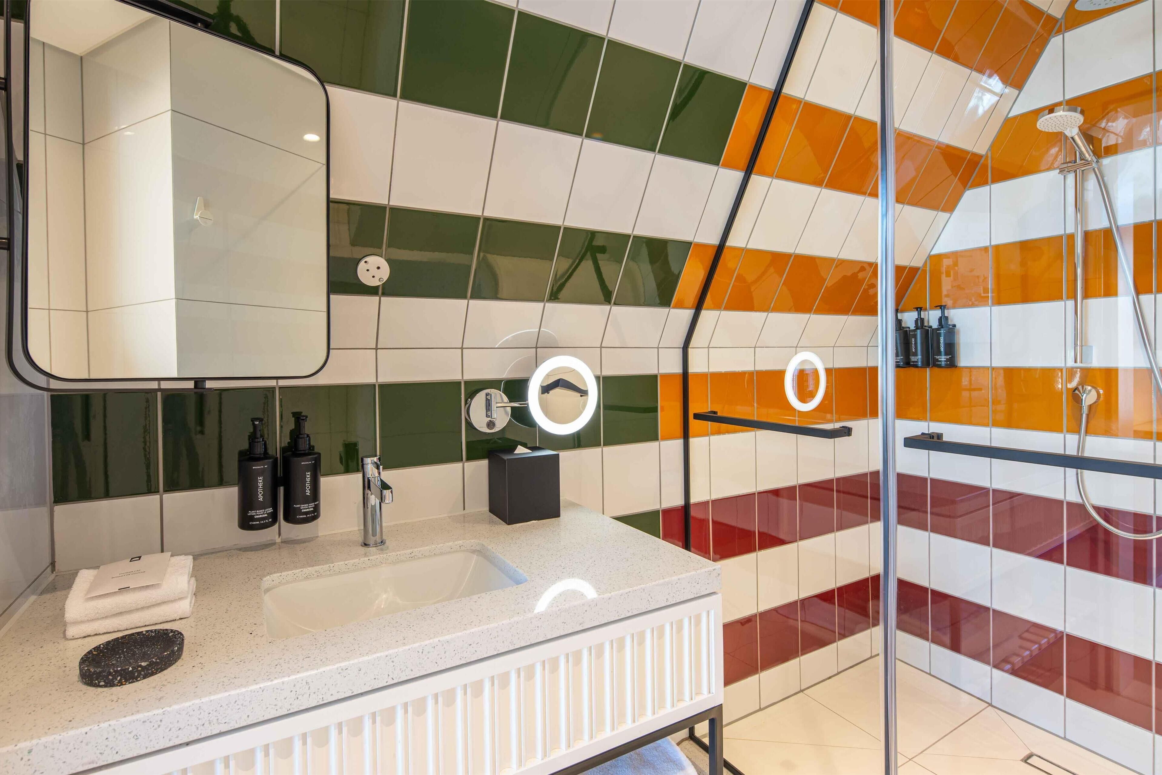 A modern bathroom with a large mirror, a sink, and a shower area.