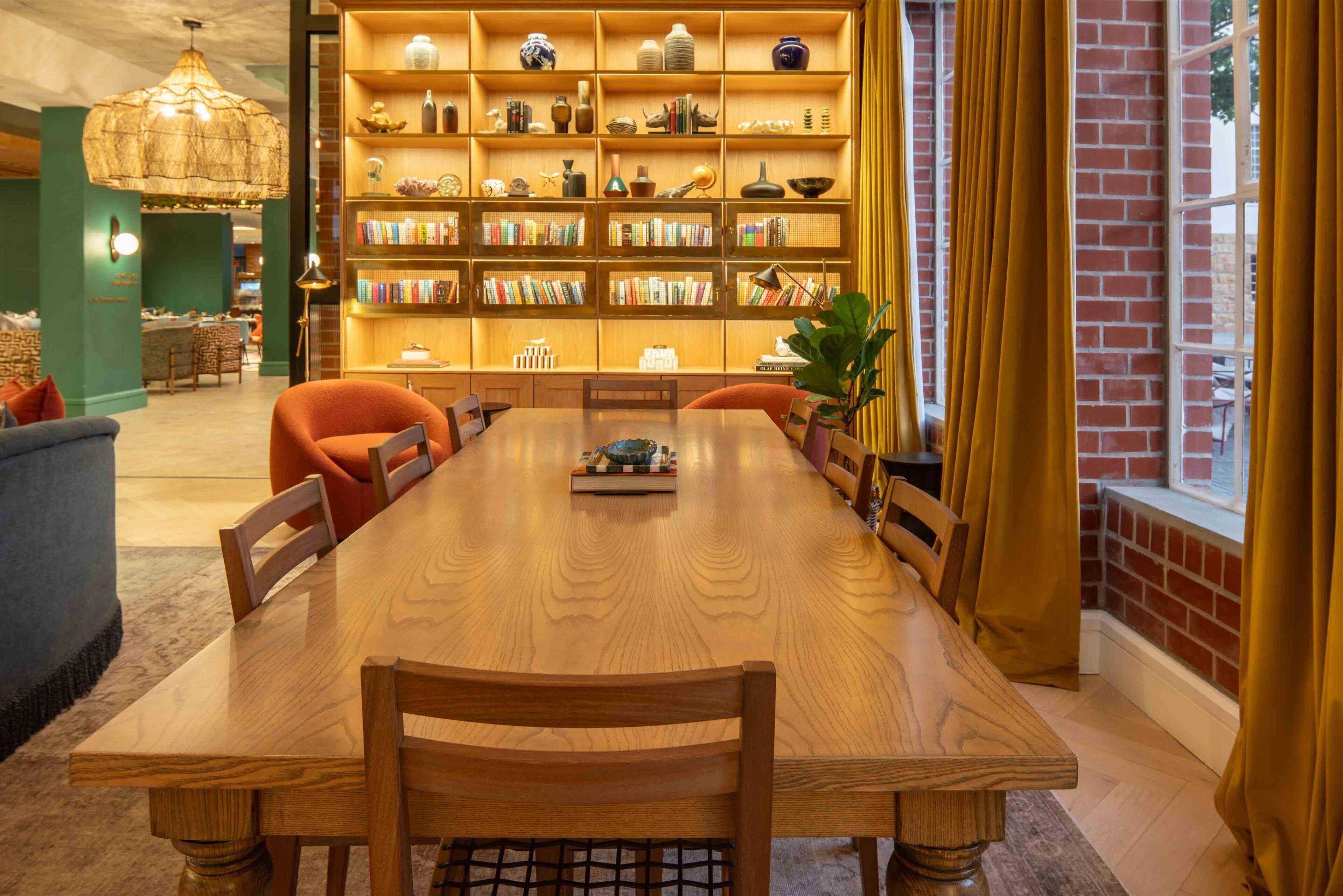 A dining area with a wooden table and chairs, surrounded by bookshelves filled with books and decorative items.