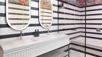 A modern bathroom with two sinks, a large mirror, and a shower area.