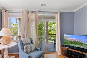 A living room with a sofa, a television, and a table with a lamp. - Mini Weeks Stays Available Sunset Island 4 Fountai (Ocean City)