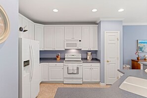 A kitchen with white cabinets, a built-in microwave, a stove, and a refrigerator.