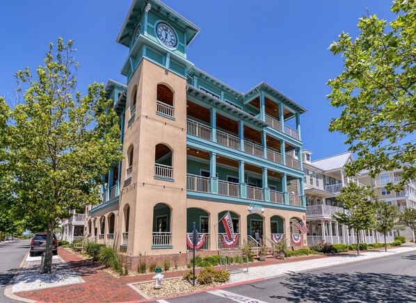 A multi-story building with a clock tower, balconies, and American flags.