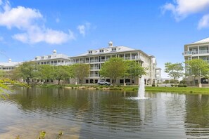 A waterfront property with multiple-story buildings, a fountain, and a clear sky.