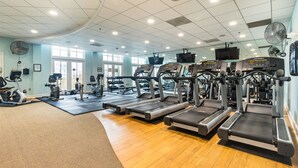 Une salle de sport équipée de tapis de course, de vélos elliptiques et de matériel de musculation.