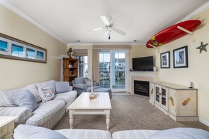 Una sala de estar con un sofá, una mesa de centro, un televisor, una chimenea y un adorno con forma de tabla de surf.