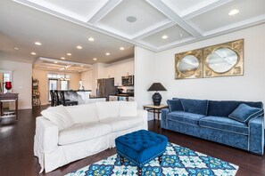 A living room with a white sofa, a blue sofa, and a blue ottoman on a patterned rug. - Broad Marsh Unit 112E (Ocean City)