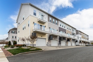 A multi-story apartment building with balconies, garage doors, and a clear sky. - Broad Marsh Unit 112E (Ocean City)