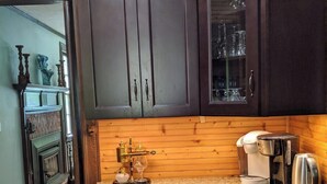 Una cocina con armarios de madera oscura, encimera de granito, cafetera y nevera para vino.