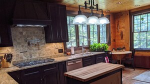Una cocina moderna con armarios oscuros, encimeras de granito y una isla central.