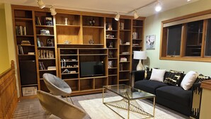 Un salon avec une bibliothèque, un téléviseur, un canapé et un fauteuil.