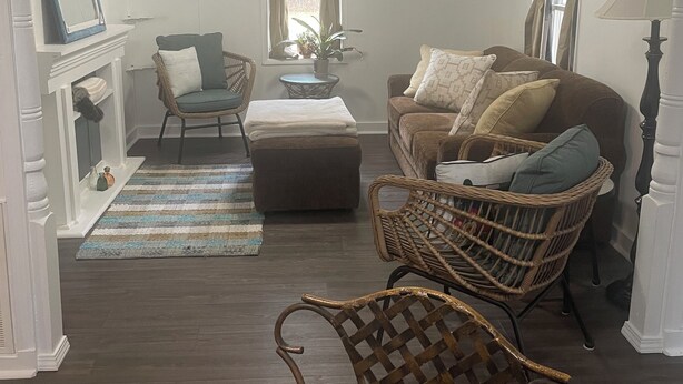 A living room with a fireplace, a sofa, two chairs, a rug, and a lamp.