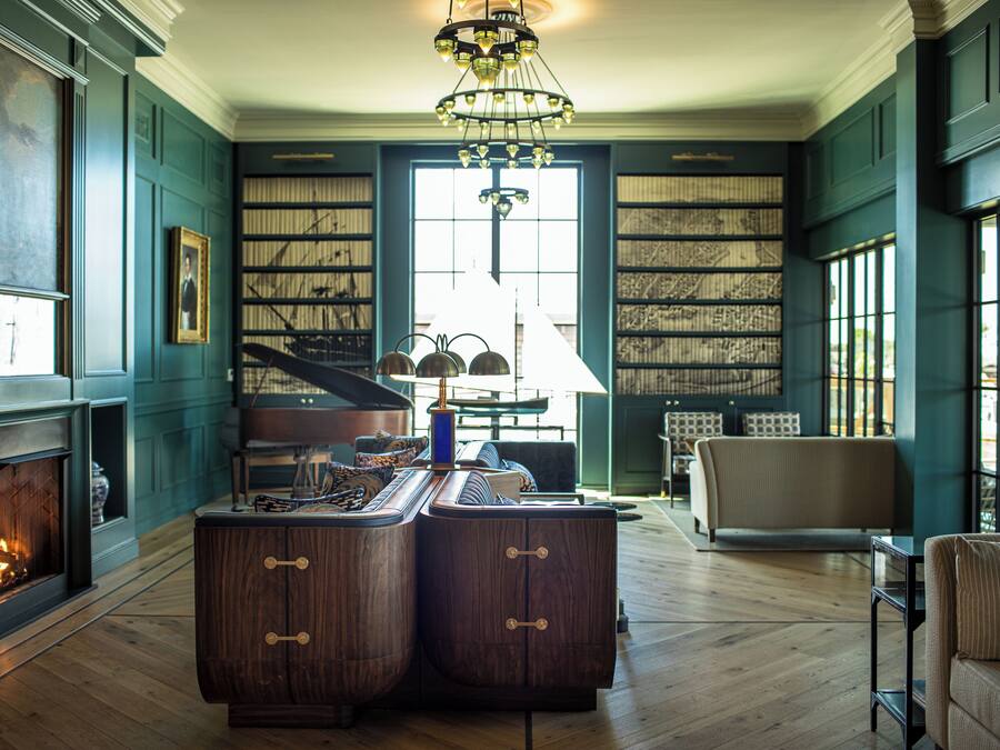 Um quarto com lareira, piano, um armário de madeira grande e estantes.