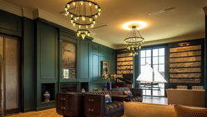A library with bookshelves, a fireplace, and a seating area with a sofa and armchairs. - DELAMAR MYSTIC (Mystic)