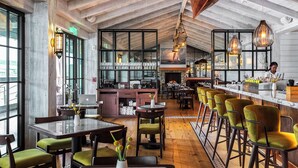 A restaurant with high ceilings, exposed beams, and a bar area with stools. - DELAMAR MYSTIC (Mystic)