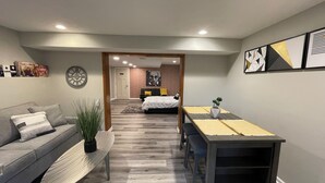 Uma sala de estar moderna com um sofá, uma mesa de jantar e uma cozinha ao fundo.