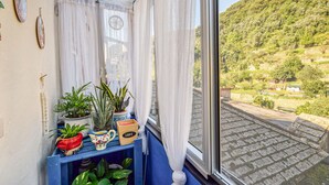 A room with a view of a hillside, a blue shelf with plants and a decorative pitcher, and sheer curtains. - Pet friendly apartment in Sori with WiFi (Sori)
