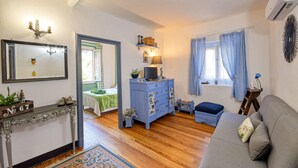 A living room with a sofa, a blue dresser, a mirror, and a window with blue curtains. - Pet friendly apartment in Sori with WiFi (Sori)