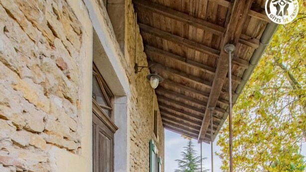 A stone building with a wooden balcony, white benches, and a metal railing. - Auprès de mon arbre - PLOTTES (PLOTTES)