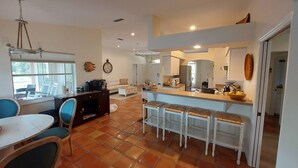 A spacious living area with a dining table, chairs, a sofa, and a kitchen area with a counter and stools.