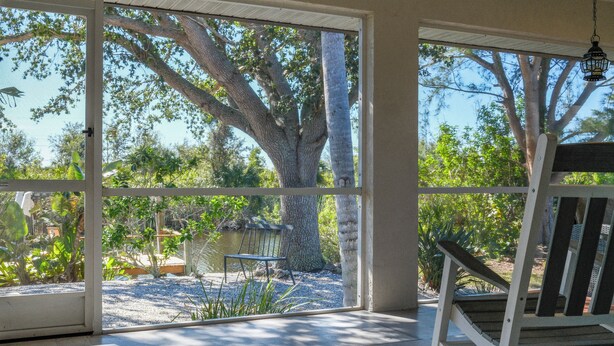 A room with large windows, a bench, and a view of a tree and garden.