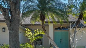 A building with a green door, a large tree, and a palm tree.