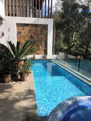 Relax by the serene pool surrounded by lush greenery and a decorative stone wall.