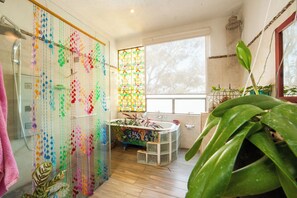 Bathroom features a unique bead-adorned wall, bathtub with mosaic tile design, and a shower area with modern faucet.