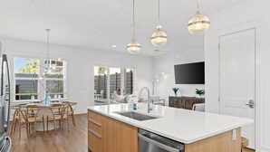 A modern kitchen with a central island, wooden cabinets, stainless steel appliances, and pendant lighting. - Take it Easy by Book That Condo (Panama City Beach)