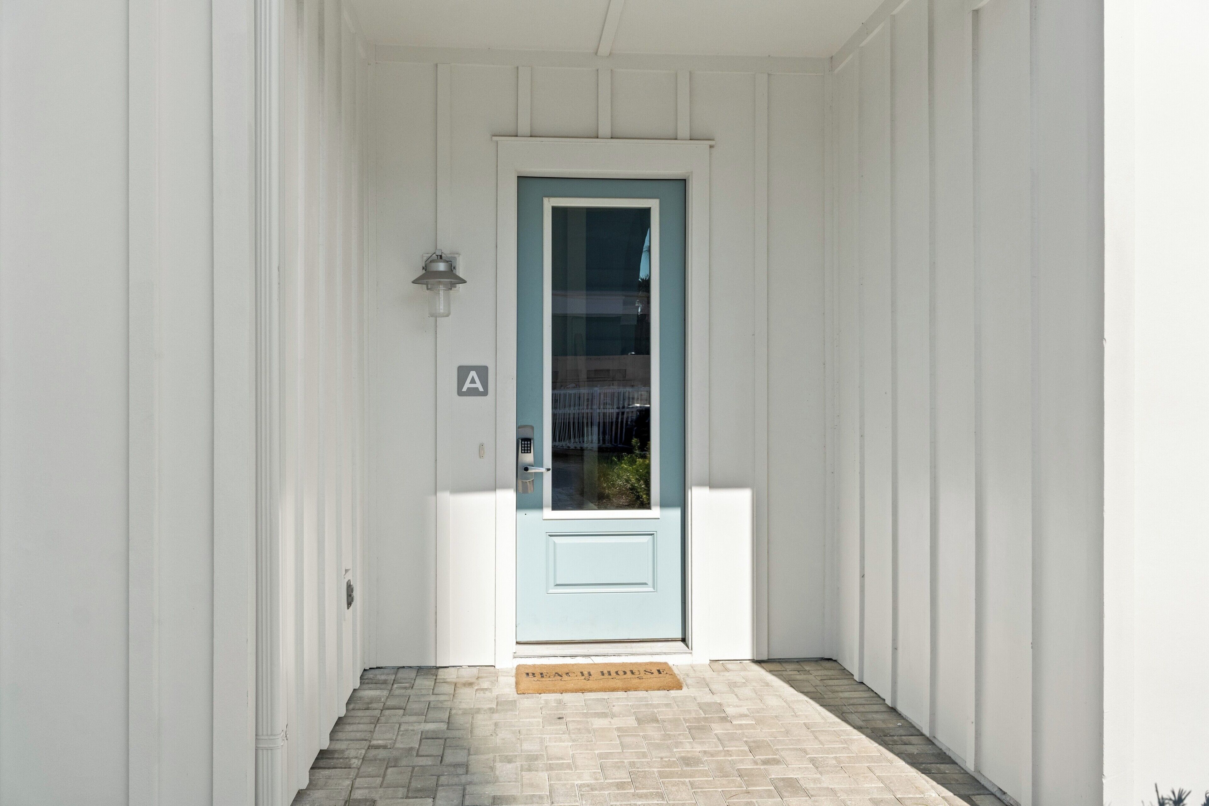 A white building with a light blue door, a small porch, and a doormat.