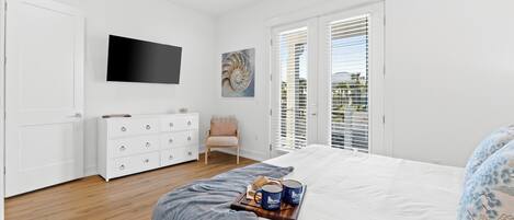 Un dormitorio con cama, cómoda, televisor y ventana con persianas.