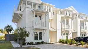A two-story residential building with a balcony on the second floor, a gated driveway, and a well-maintained lawn. - Take it Easy by Book That Condo (Panama City Beach)