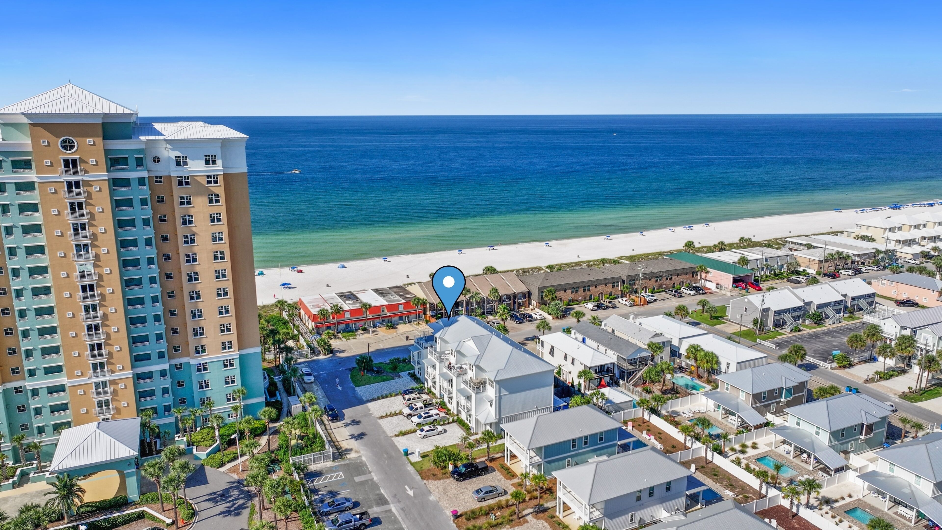 Un hotel sul lungomare con vista sulla spiaggia, diversi edifici e un'area parcheggio.