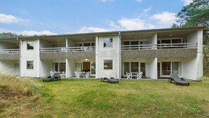 A two-story building with a balcony, outdoor seating, and a grassy lawn.