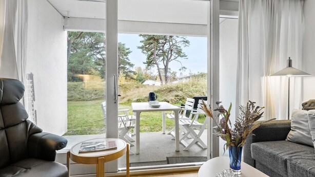 A modern living room with a sofa, a coffee table, and a dining area with a table and chairs.