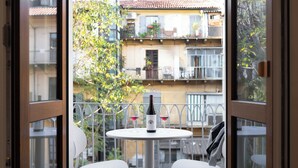 Un balcón con una mesa, dos sillas, una botella de vino y dos copas.