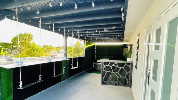 Un espacio al aire libre techado con mostrador, lámparas colgantes y un muro con diseño.