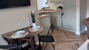 A dining area with a wooden table, black chairs, and a television mounted on the wall.