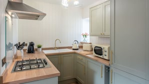 A kitchen with a gas stove, a sink, a microwave, and cabinets.