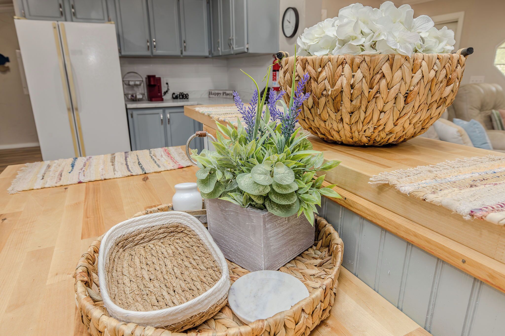 Une cuisine avec un plan de travail en bois, un panier tressé, une plante en pot et un plateau tressé.