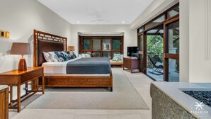 Camera moderna con un ampio letto, una testiera in legno e vista su una zona esterna tramite una porta scorrevole in vetro.