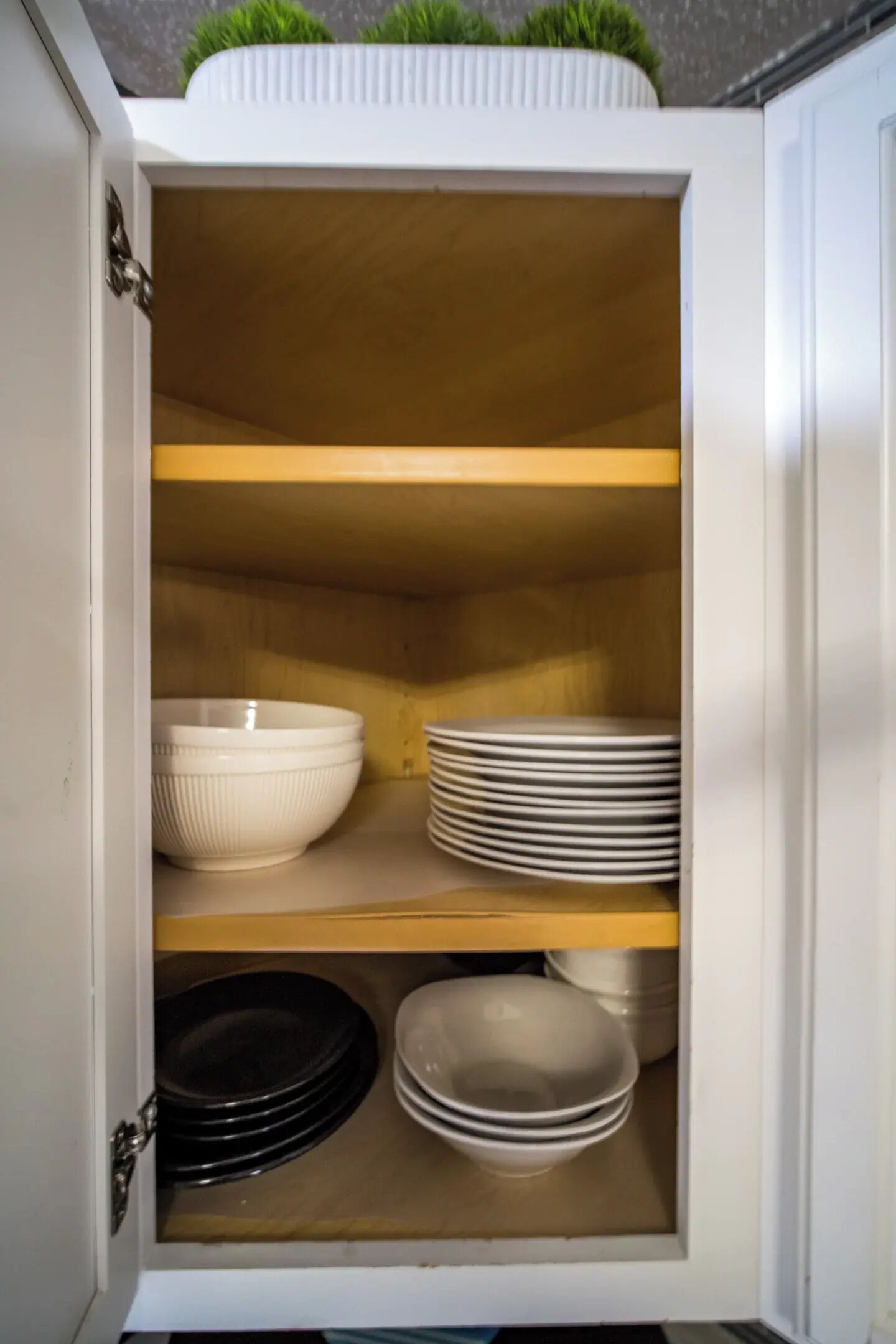 Un mueble con estantes que contiene cuencos blancos, platos y platos negros.