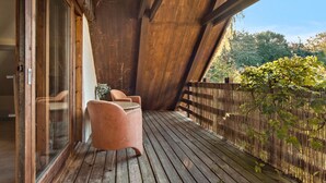 A wooden deck with a glass door leading to a room, a wooden fence, and a chair.