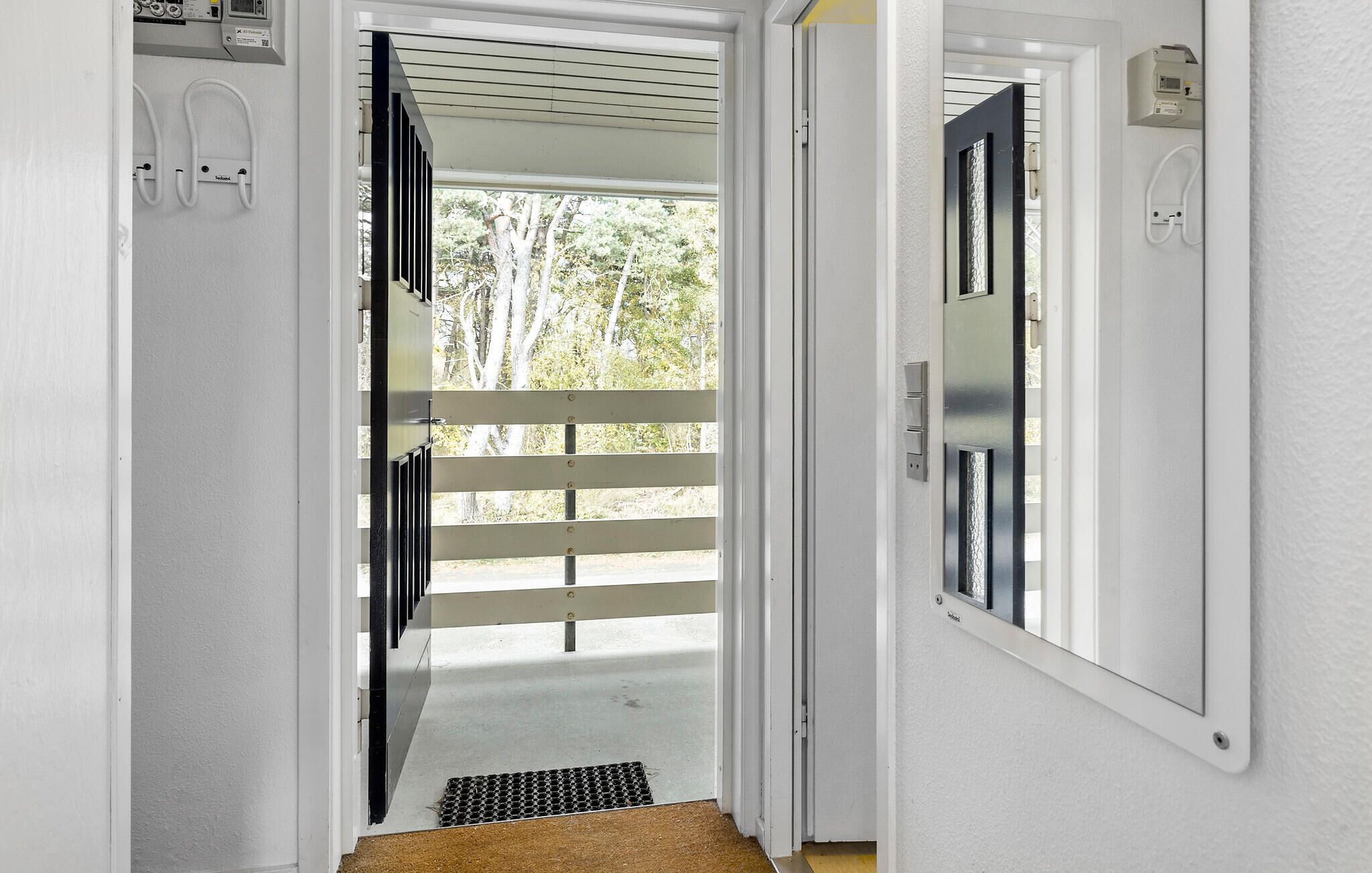 Ein Flur mit einer Tür, die auf einen Balkon mit Metallgeländer führt.