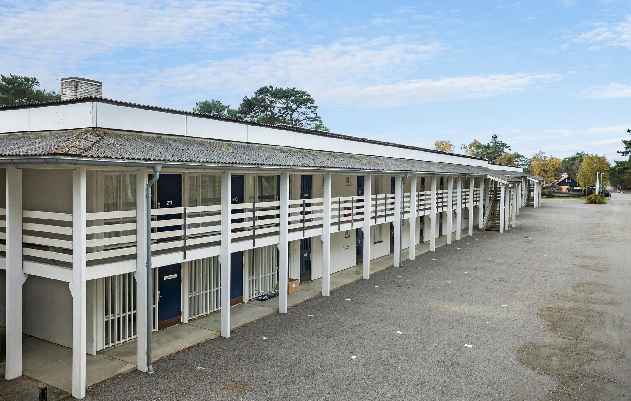 A row of white, single-story buildings with numbered windows, likely a stable or storage facility.