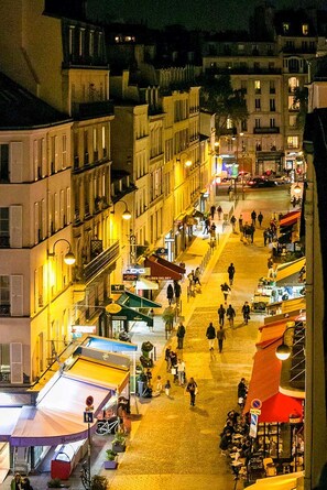 A nighttime view of a bustling street with buildings, shops, and pedestrians. - Eiffel Tower – Les Invalides, 10 minutes away   (Paris)