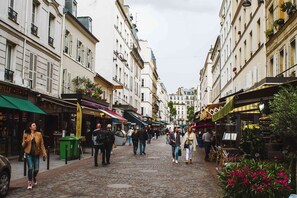 A cobblestone street lined with buildings, shops, and outdoor seating areas. - Eiffel Tower – Les Invalides, 10 minutes away   (Paris)