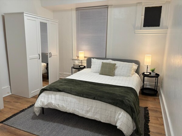 A bedroom with a bed, bedside tables, a wardrobe, and a window with blinds. - Steel City Stay- 4B/2B Getaway (Pittsburgh)