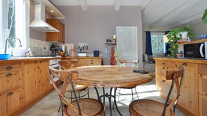 A modern kitchen with wooden cabinets, a central island with chairs, and a dining table. - Amazing home in Besse-sur-Issole (Besse-sur-Issole)