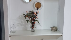 Et badeværelse med hvid kommode, tre runde spejle, en vase med blomster og en lille kurv.