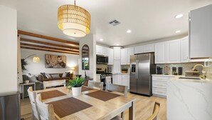 Una cocina moderna con armarios blancos, electrodomésticos de acero inoxidable y una isla de mármol.